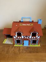Front exterior of Fisher-Price Tudor-style dollhouse with garage and carry handle