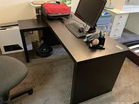 Full view of L-shaped desk with computer setup and chair showing color and form