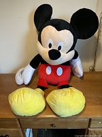 Full view of oversized Mickey Mouse plush seated on table