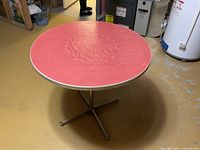 Full view of red laminate round table on chrome four-star base