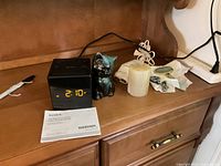Sony clock radio, cat figurine, candle, cords and manual on shelf