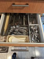 Drawer view showing chopsticks, assorted spoons, forks and plastic rice paddles