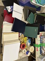 Pile showing various bound journals, spiral notebook, pads and several spools of twine in assorted colors