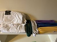 Folded Panda Brand white gi with visible 1971-1995 patch and belts in five colors