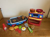 Entire toy kitchen set with stove, griddle, cookware, utensils and play food arranged on tabletop