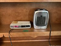Heater and clock radio side by side on shelf showing overall lot