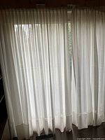 Full view of both sheer curtain panels closed across window on ceiling track