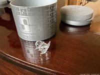 Faceted crystal bird figurine beside original grey cylindrical Swarovski Silver Crystal box and foam insert