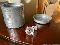 Figurine beside original cylindrical box and lid on tabletop
