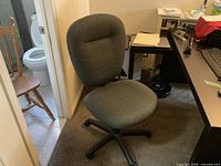 Full view of gray armless office chair beside desk