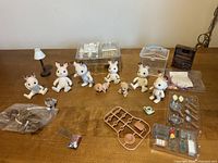 Group shot of figures, carry cases, hutch, lamp, crib and accessories spread on table