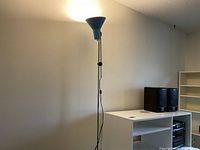 Full view of teal floor lamp lit against wall