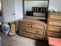 dresser with mirror, tall chest and headboard visible
