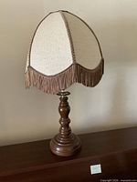 Full view of lamp showing wood base and fringed shade