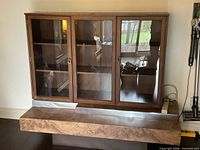 Front view of cabinet with closed glass doors showing walnut veneer and base