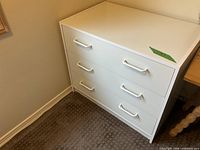 White dresser showing top and three visible drawer fronts with twin white handles