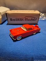 red Brooklin Models die-cast car front/side view with box in background