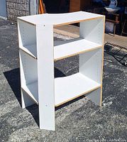 Front angled view of white corner shelf unit with three tiers