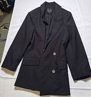 Full view of black double-breasted blazer laid flat