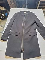 Full view of black long blazer coat laid flat showing overall design