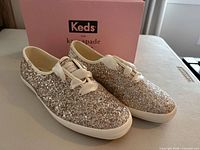Full view of both glitter sneakers beside original box