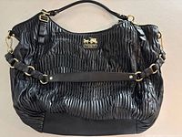 Front view of pleated leather Coach tote showing logo plaque, hardware, and strap configuration