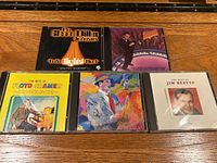 All five CDs with jewel cases displayed on wooden surface