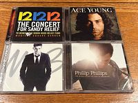 Top left 12-12-12 concert CD, top right Ace Young CD, bottom left Michael Bublé CD, bottom right Phillip Phillips CD