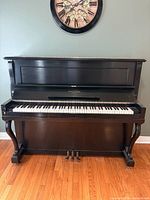 Front view of upright piano showing full keyboard and pedals