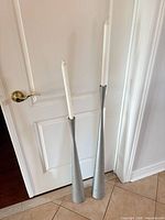 Pair of tall brushed silver metal candle holders with taper candles for scale