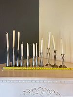 All 11 candlesticks with candles lined up by height beside measuring tape