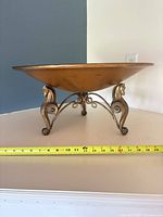 Wide shot of brass bowl on horse-motif legs with tape measure showing diameter