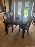Dark wooden dining table with four cream fabric chairs around it