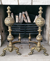 Both brass andirons positioned in fireplace opening
