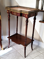 Three-quarter view of full table showing marble top, brass gallery, legs, lower shelf