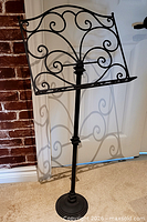Full view of the cast iron music stand showing base, vertical column and scrollwork holder