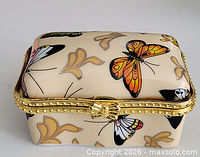 Front angled view showing butterfly clasp, gold-tone rim and decoration