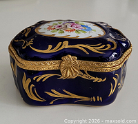Front view of cobalt blue porcelain trinket box showing brass clasp and gilt decoration