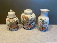 Three matching Satsuma-style porcelain pieces—two ginger jars with lids and one bud vase—grouped together