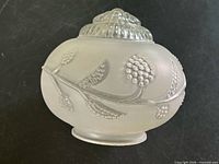 Side view of frosted glass shade showing raised floral and berry detailing and ribbed top