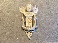 Front view of cast iron cherub door knocker showing motif and paint wear