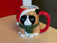 Front view of sculpted Grumpy Cat mug showing face, Santa hat, scarf, handle
