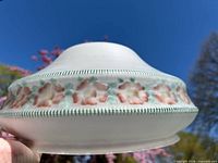 Side profile showing frosted glass shade with floral band under natural light