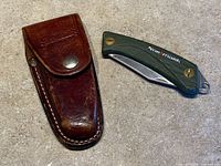 Knife folded next to brown leather sheath
