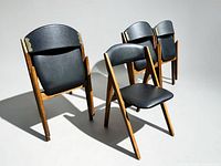 Three chairs unfolded showing front and side profile, wood frames and black vinyl seats visible