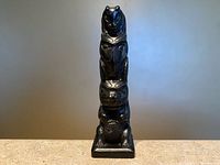 Full front view of 4-inch black faux argillite totem pole on plinth