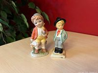 Two vintage boy figurines side by side