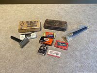 Group shot of all items: two razors, sealed handle, Tech box, metal case, seven blade packs