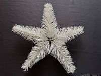 front view of white bristle star tree topper showing full shape and bristle texture