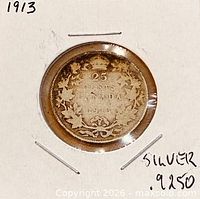 Reverse of 1913 Canadian 25-cent coin in holder showing denomination and wreath design